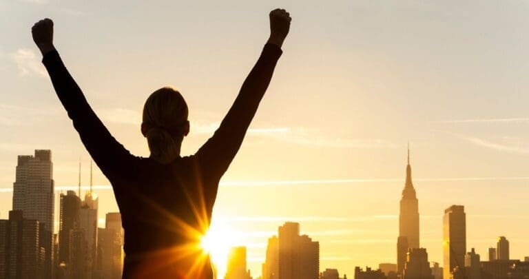 5 Steps to Success: Silhouette of a triumphant person raising arms in victory against a city skyline at sunrise, symbolizing the achievement of personal and professional goals