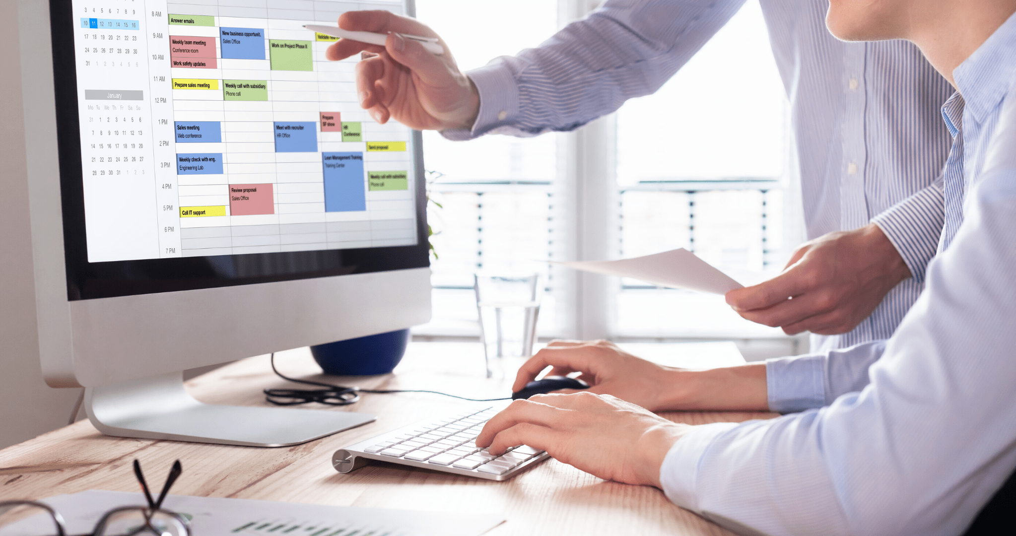 Office colleagues collaborating to plan their schedule on a computer, avoiding time management mistakes.