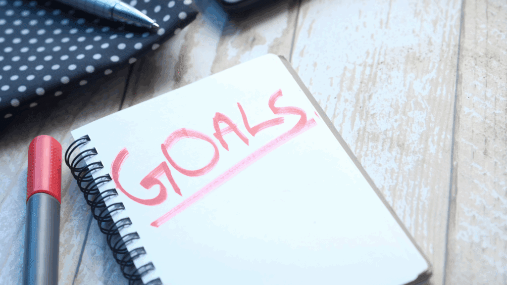 Close-up of a notepad with the word Goals written in red, representing self-driven goal setting.