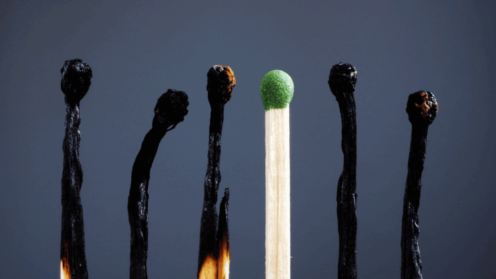 Burnt matches stand out from a single green match, symbolizing burnout and standing out from the crowd.