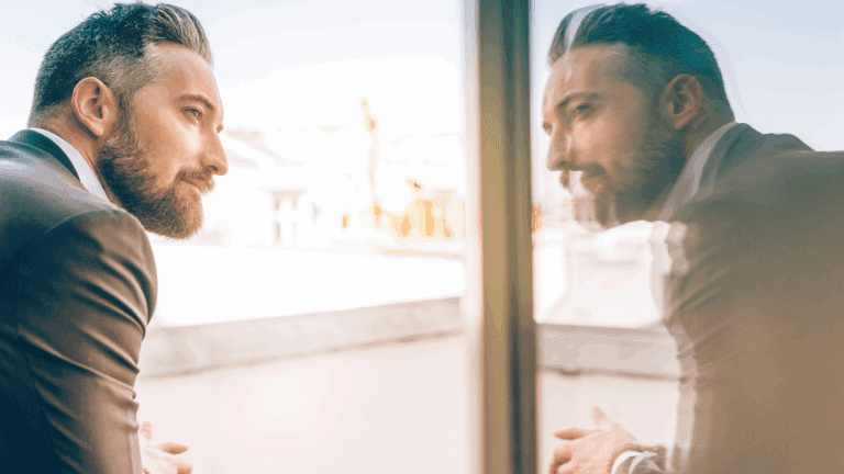 Man looking out window with Self-Awareness as he sees his reflection