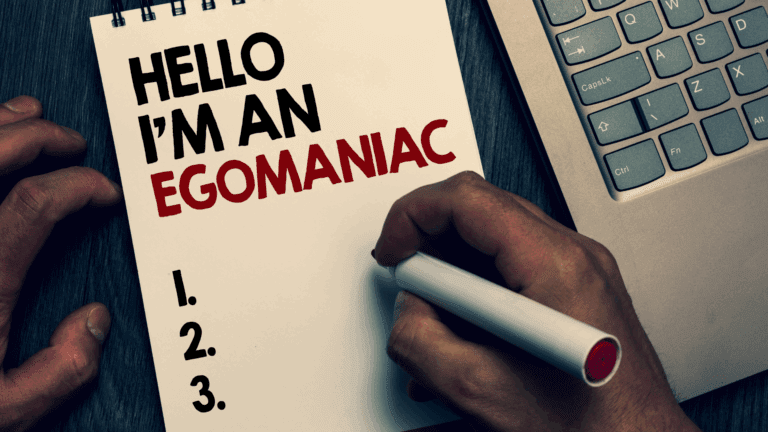 Notebook with "Hello I'm an Egomaniac" written on it next to a laptop referencing narcissism.