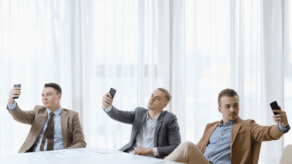 Three businessmen taking selfies, symbolizing an inflated ego.
