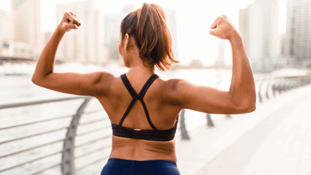 Athletic woman flexing muscles demonstrating inner strength and physical courage