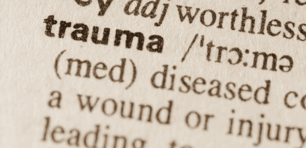 Close-up of the word 'trauma' in a dictionary, emphasizing its definition.
