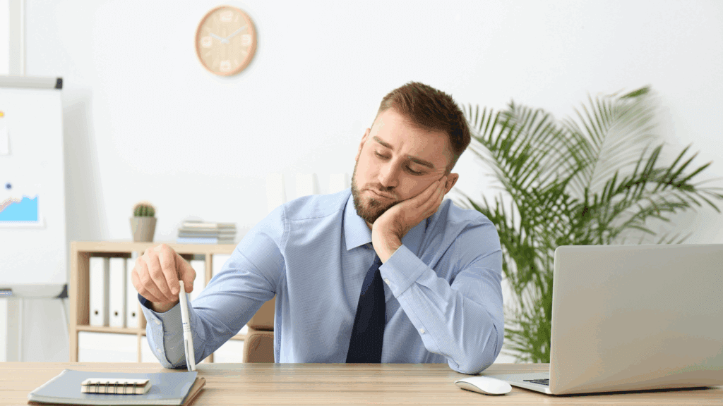 Man sitting at a desk appearing bored
Alt: Businessman sitting at a desk looking bored and unmotivated.