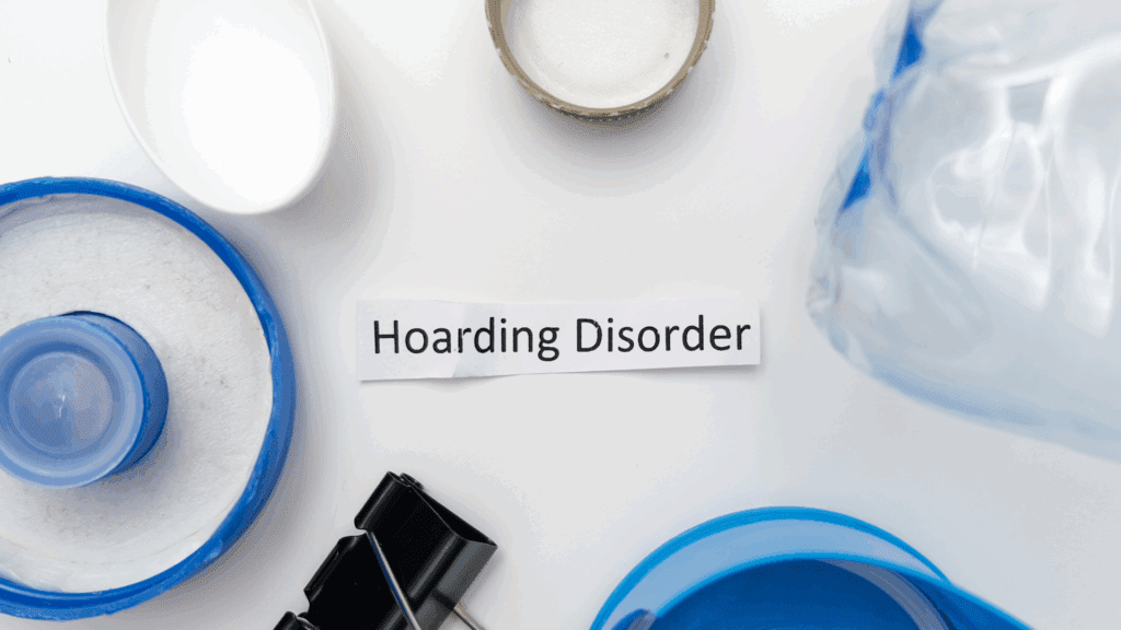 A sign reading "Compulsive Hoarding" surrounded by miscellaneous clutter, symbolizing the disorders impact.

