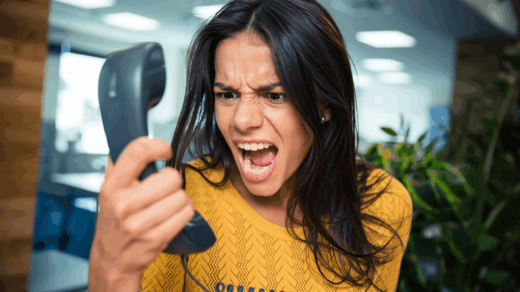 A woman in an office setting yelling into a phone, showing frustration in workplace interactions.