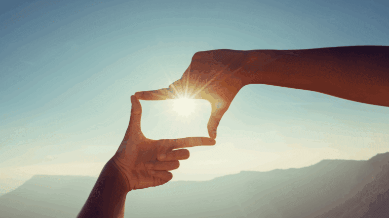 Hands framing sunlight over mountains, symbolizing the neuroscience of perspective
