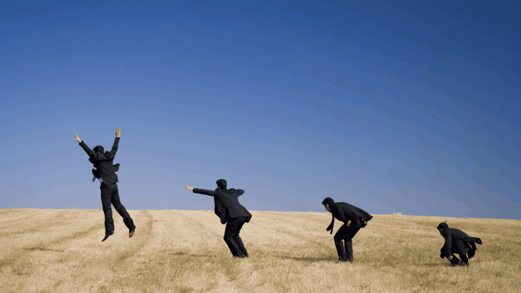 A sequence of a businessman in a suit jumping in a field, illustrating evolution and the neuroscience of anxiety.
