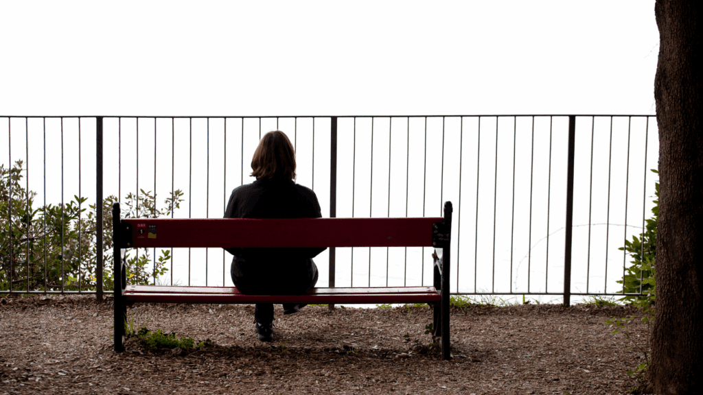 Person sitting alone on a bench, symbolizing isolation and loneliness in the neuroscience of sex addiction
