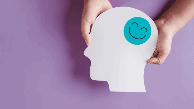 Paper cutout of a human head with a happy face symbol, representing the dopamine paradox in brain reward systems.