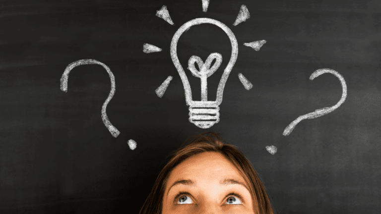 Woman looking up at a chalkboard with a lightbulb and question marks, symbolizing curiosity and thinking dispositions.